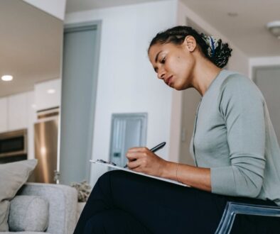 concentrated ethnic female interviewer or psychotherapist taking notes in clipboard