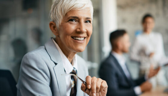 Portrait of happy mature businesswoman at corporate office looking at camera.